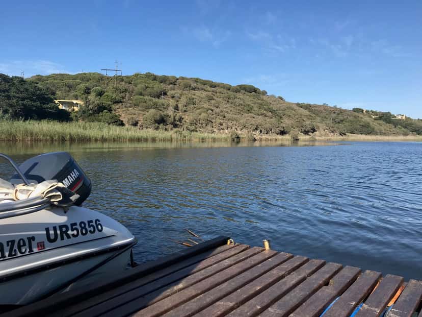 The Goukou River from the farm jetty: a boat moored alongside, blue water and wooded hills.