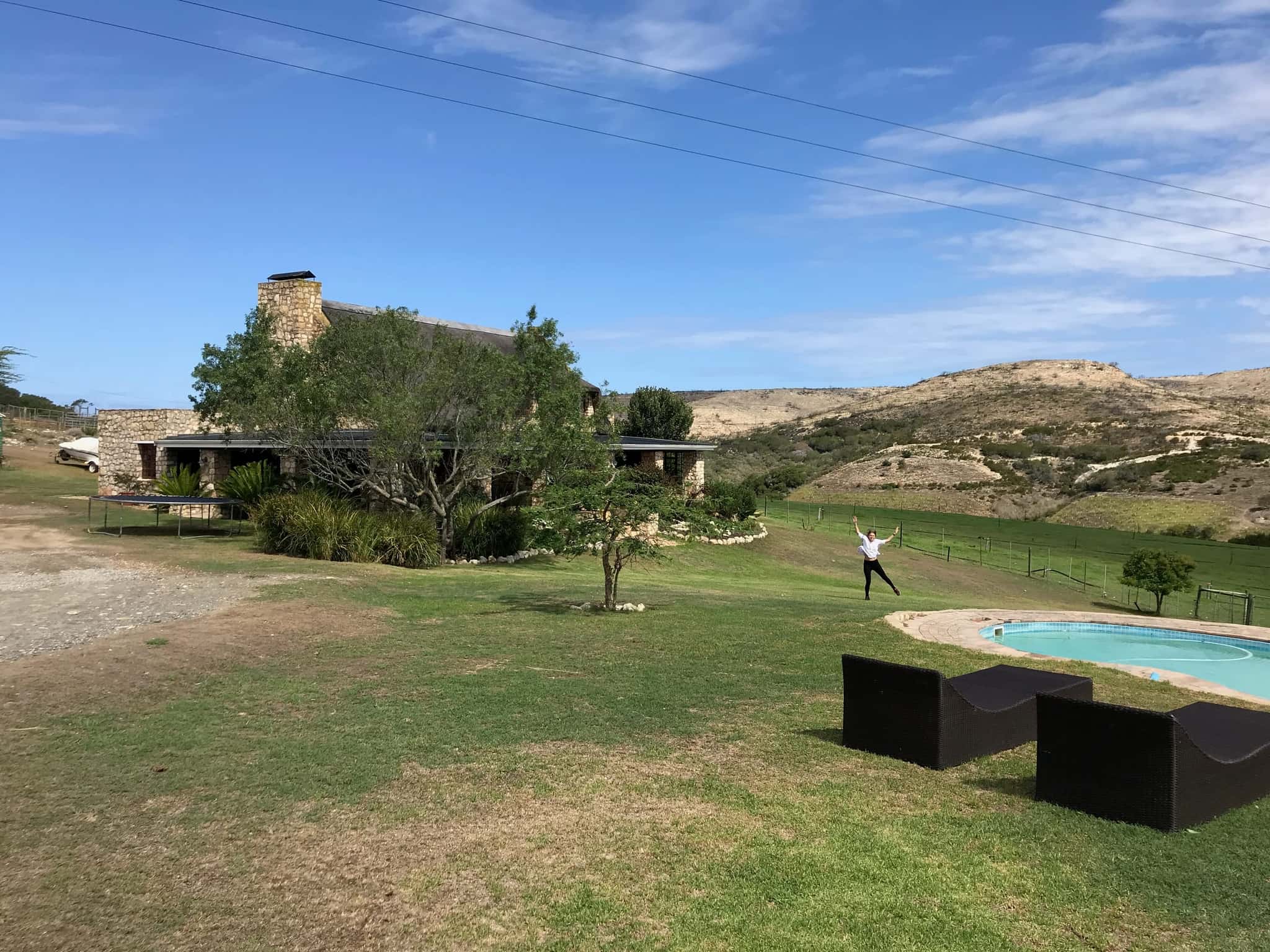 Stonehouse Lodge, the thatched stone house, with its pool on the lawn and the hills of the Goukou valley behind.