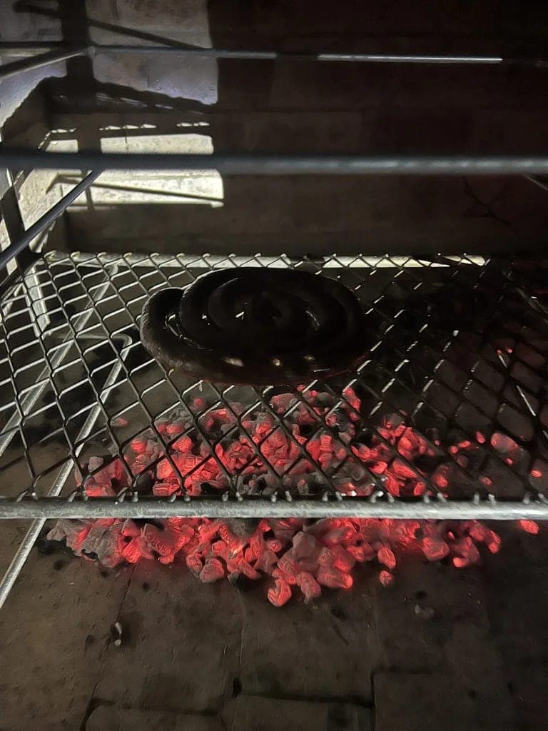 Coals glowing red under the grid of the stone braai.