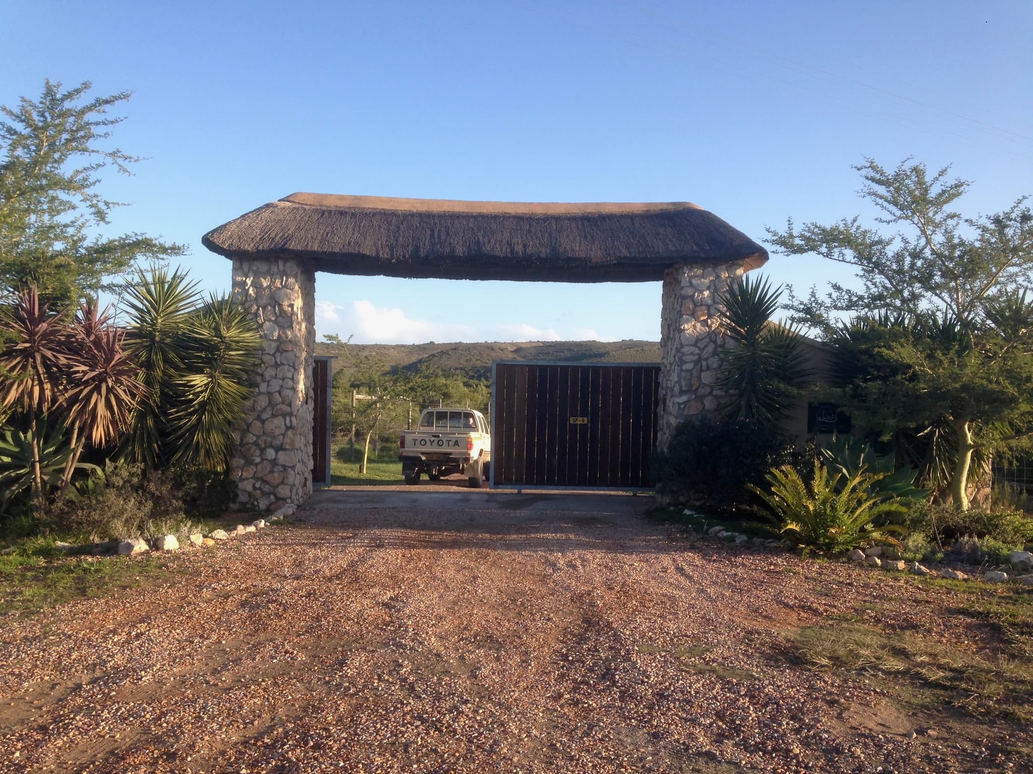 The farm gate under a stone and timber archway at the end of the gravel road.