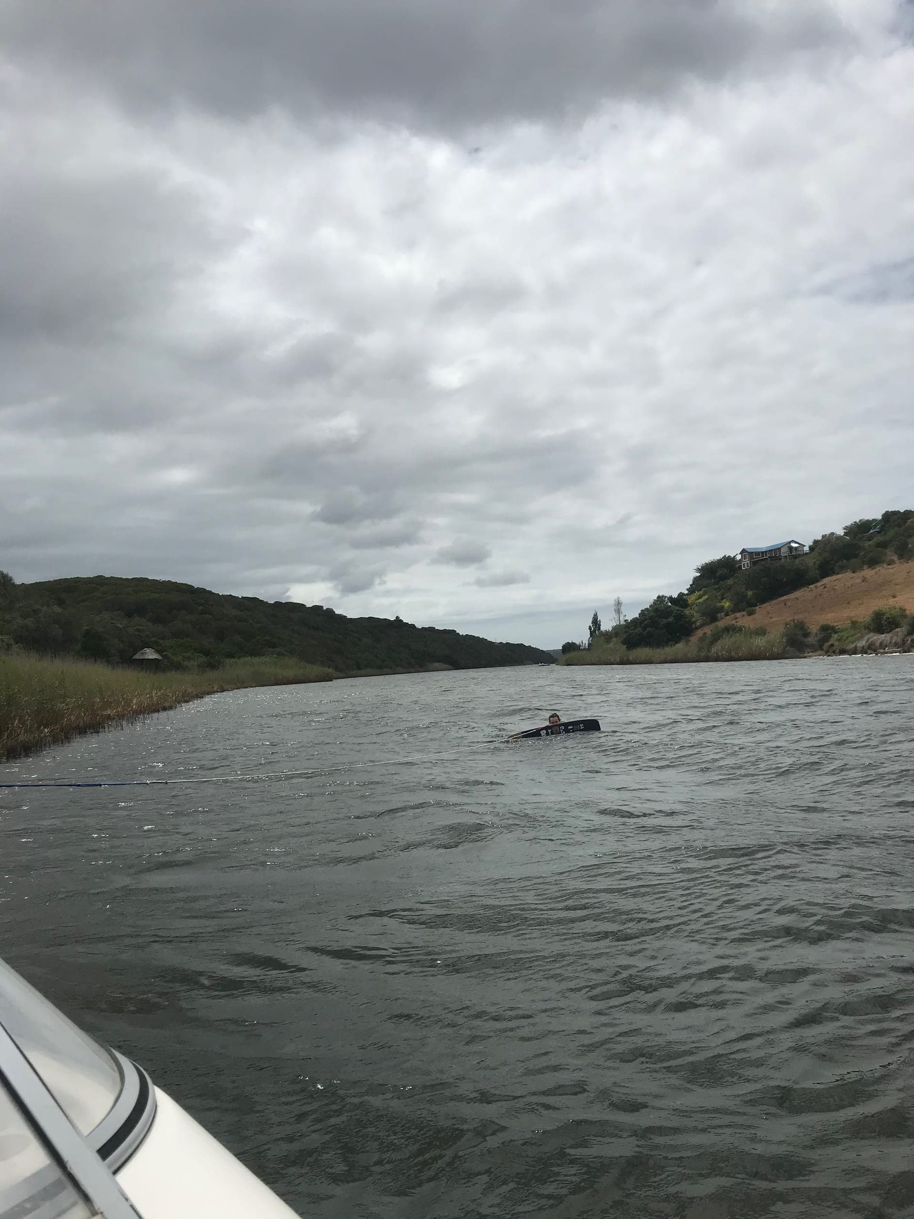 Looking down the Goukou from a boat on a cloudy day, wooded slopes on both banks.