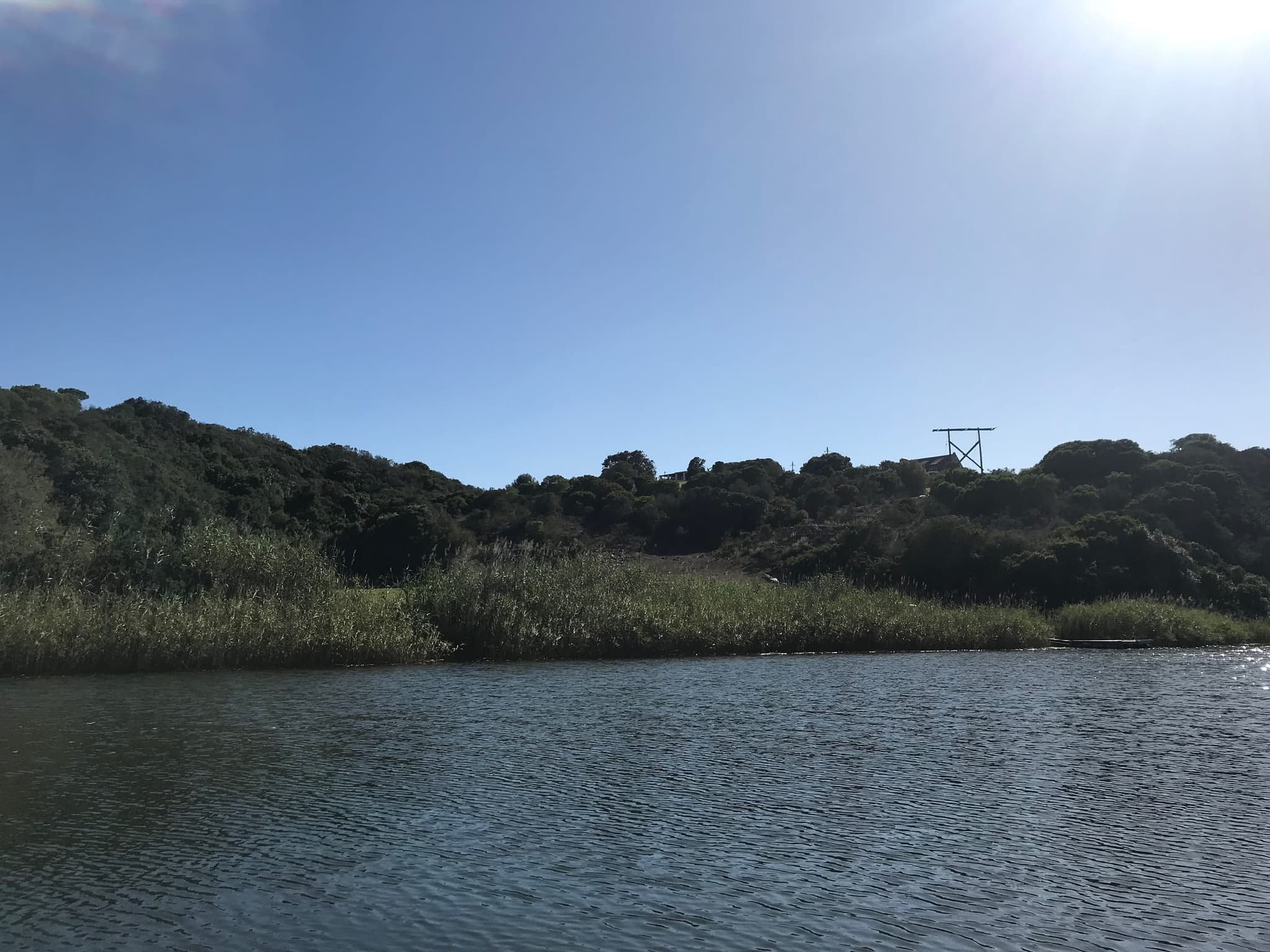 The Goukou River between thickly wooded banks under a bright sky.
