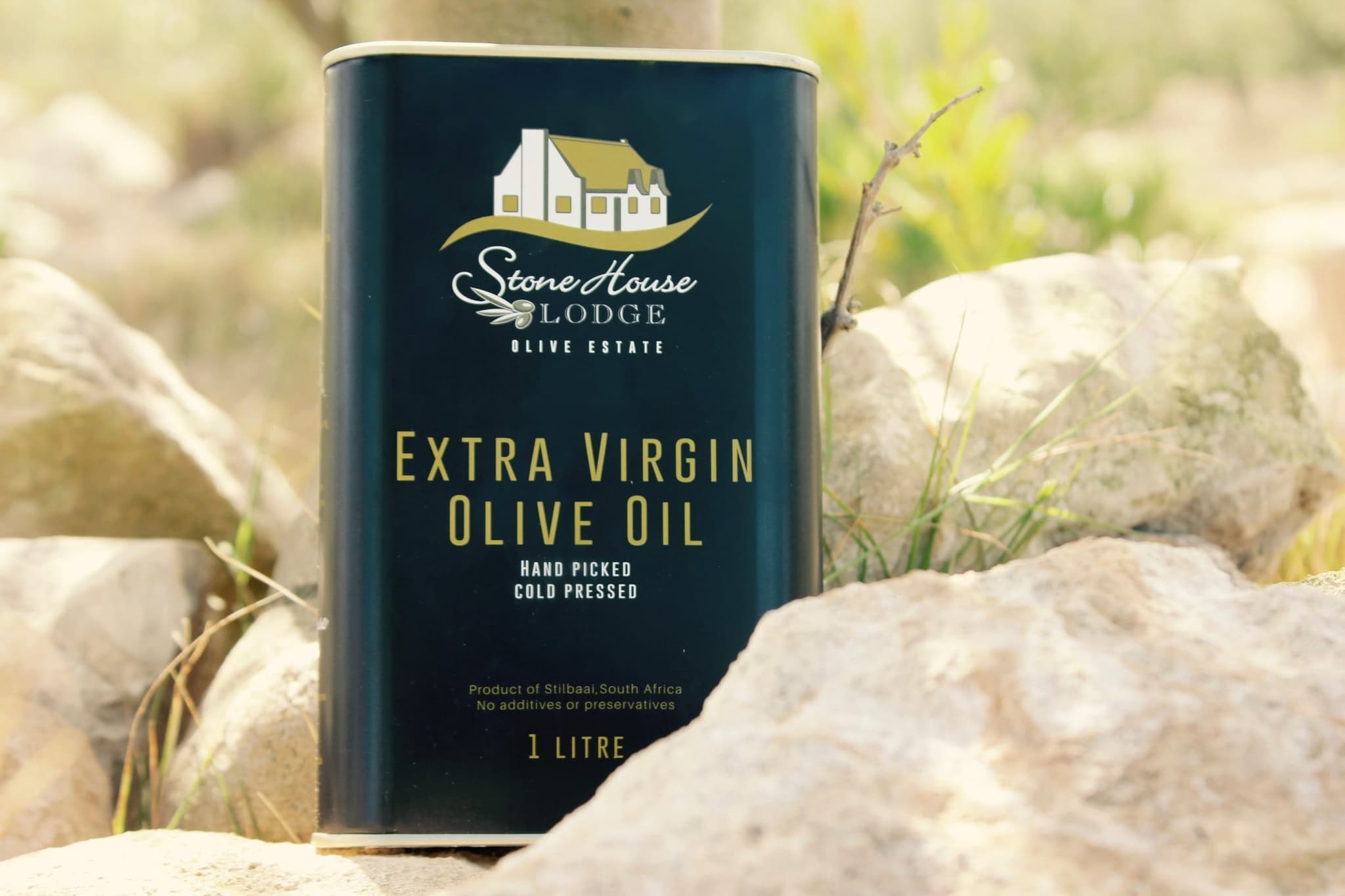 A one-litre tin of Stonehouse Lodge extra virgin olive oil, hand picked and cold pressed, standing on a rock.