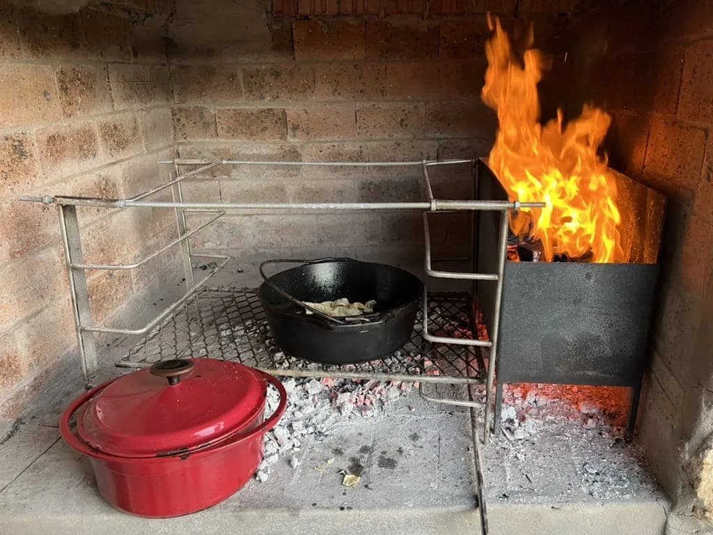 Cast-iron potjie pots cooking over the fire in the stone braai.