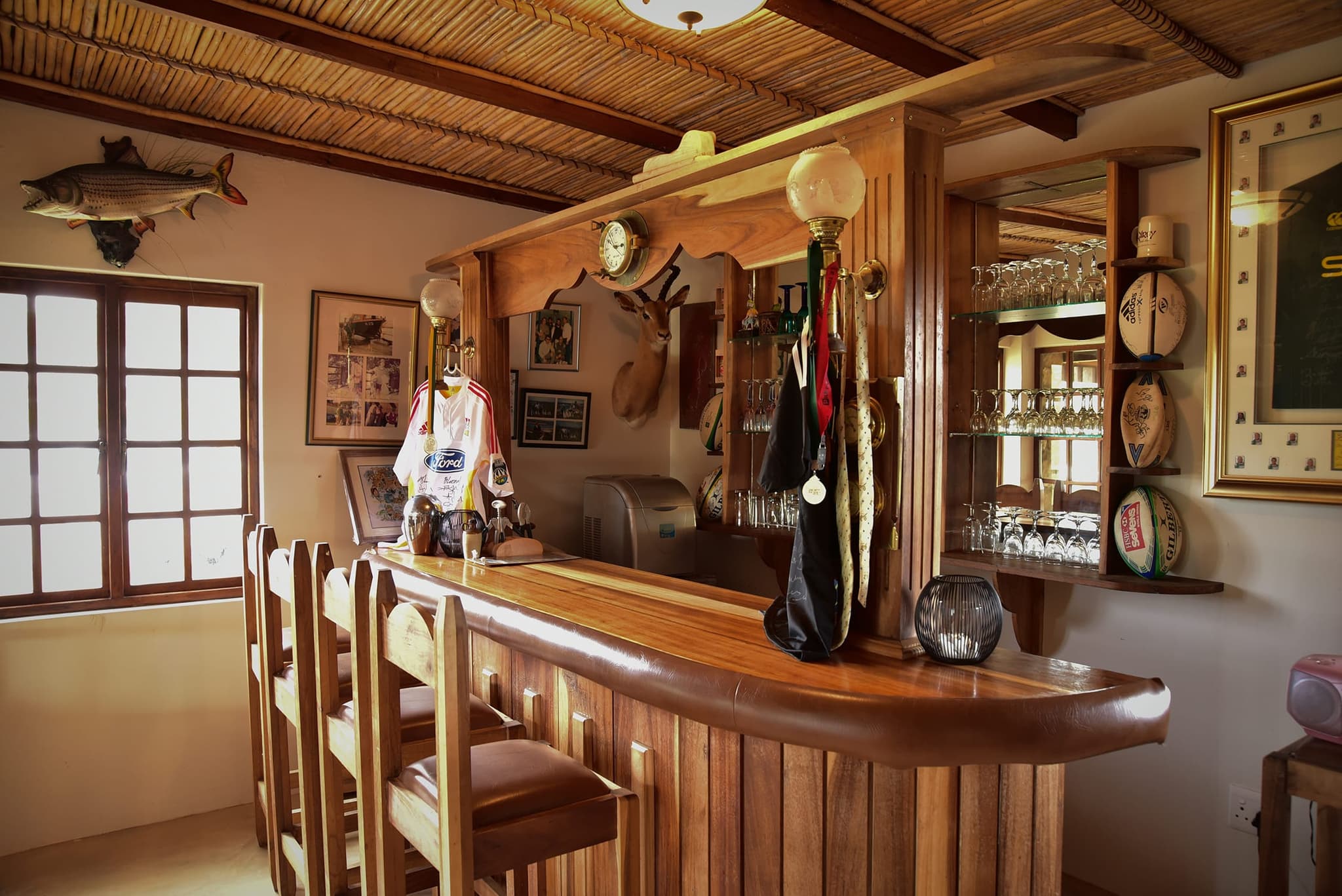 The wooden bar counter and bar stools inside Stonehouse Lodge, with fishing trophies on the walls.