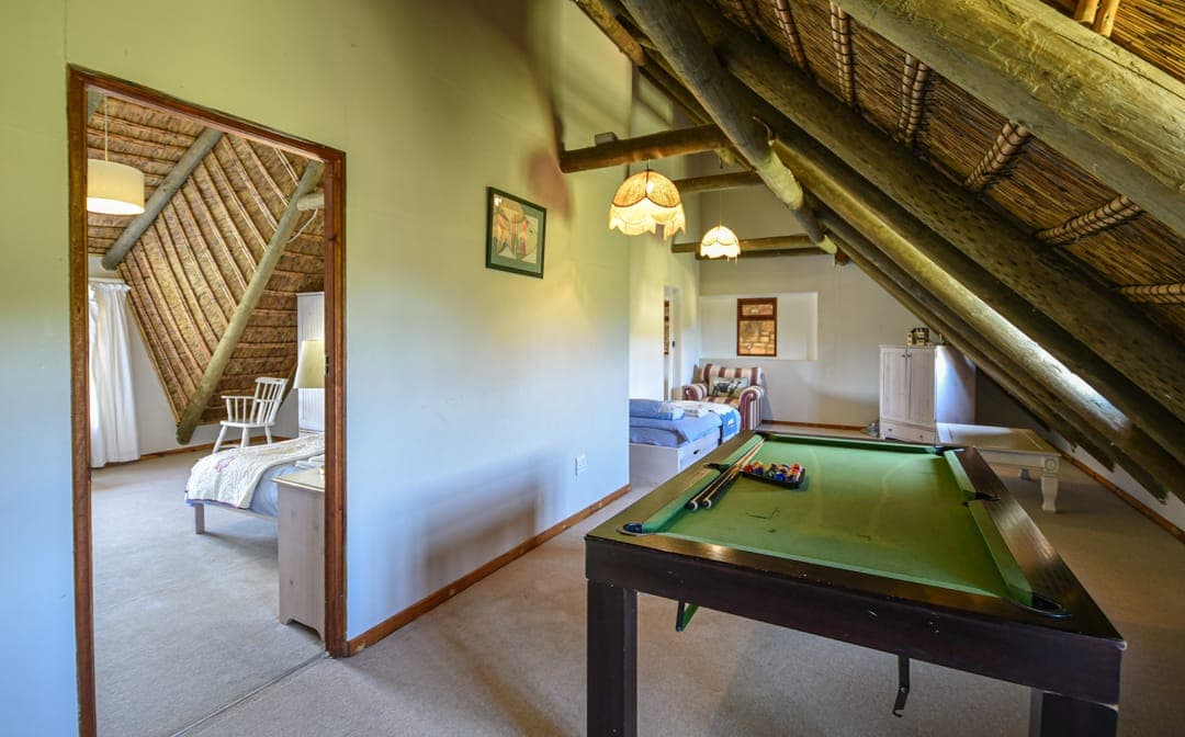 The pool table on the upper landing of Stonehouse Lodge, beneath the thatch beams.