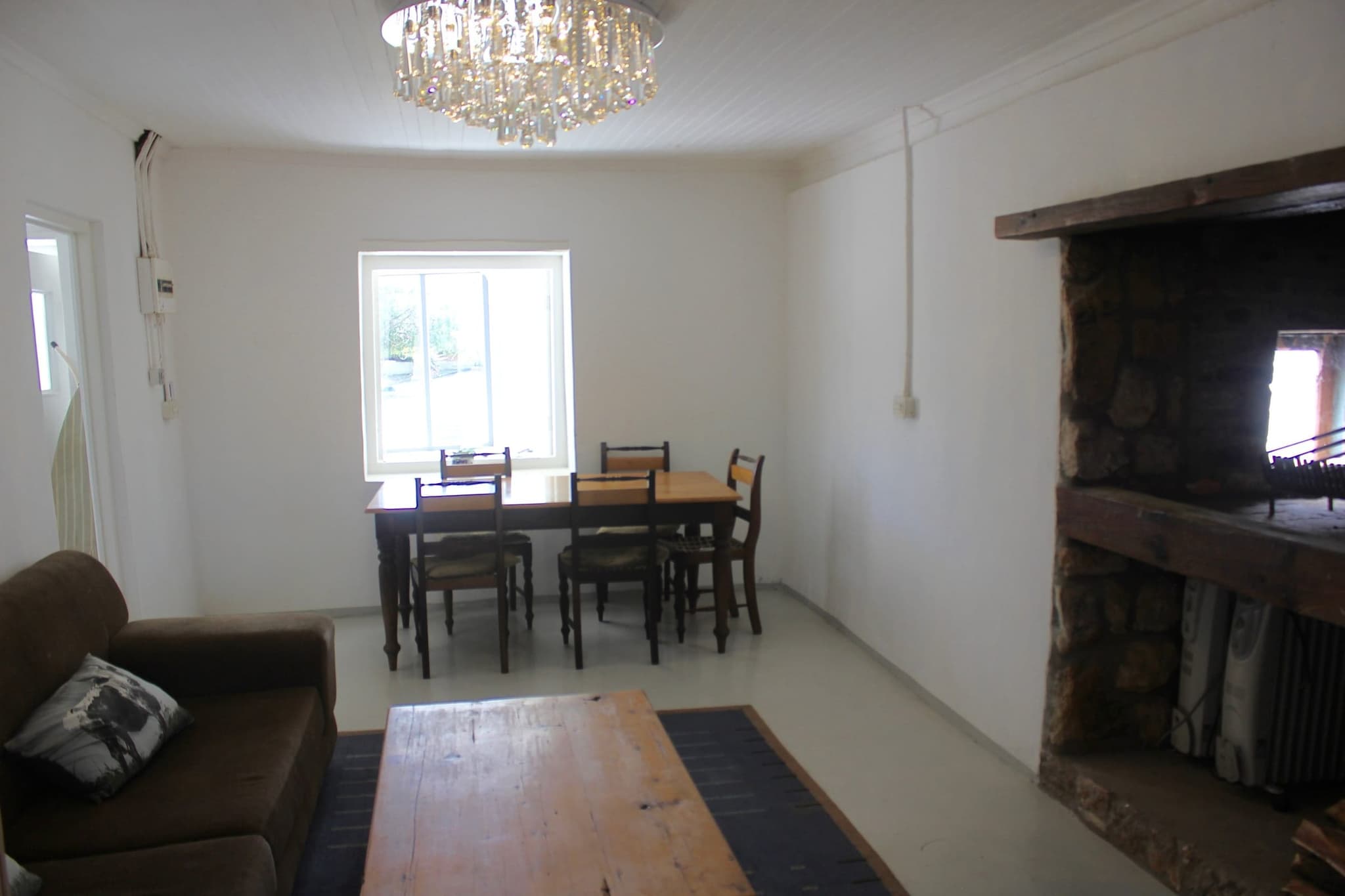 The White House Cottage dining room: a table for six under a crystal chandelier, beside the stone fireplace.