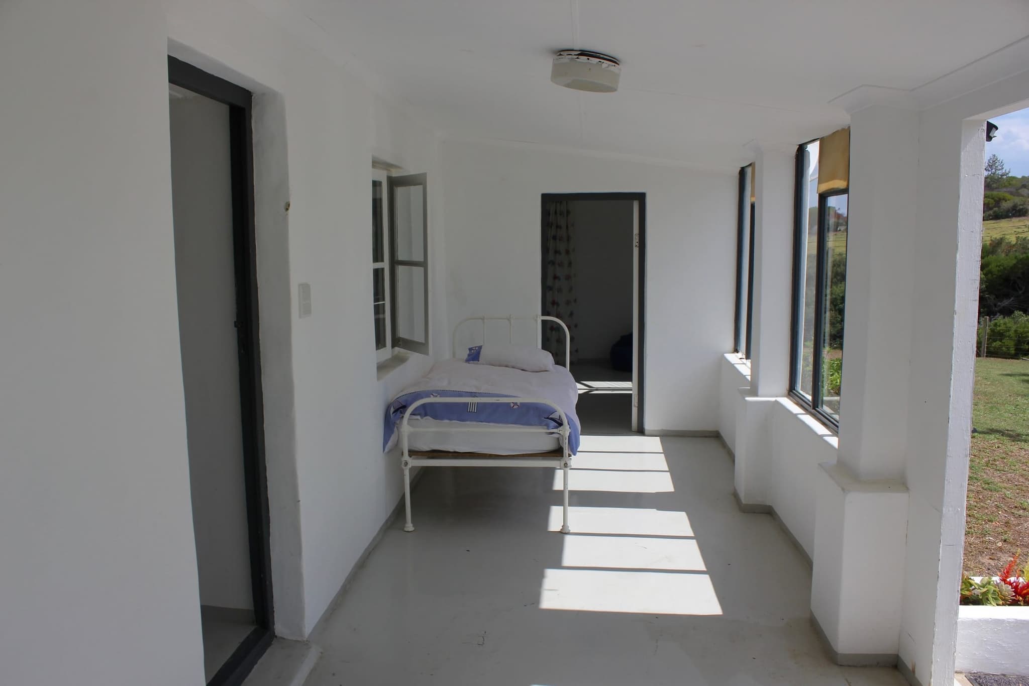 The light-filled entrance room at White House Cottage, with a single bed by the windows.