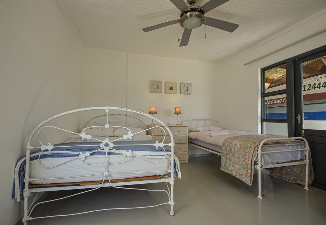 The family room at White House Cottage: a white iron double bed and a single bed under a ceiling fan.