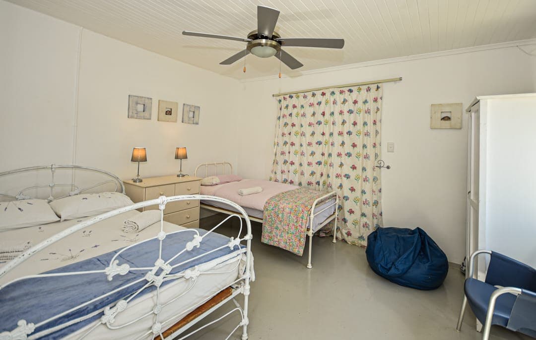 A family bedroom at White House Cottage with a double bed and single beds under a ceiling fan.