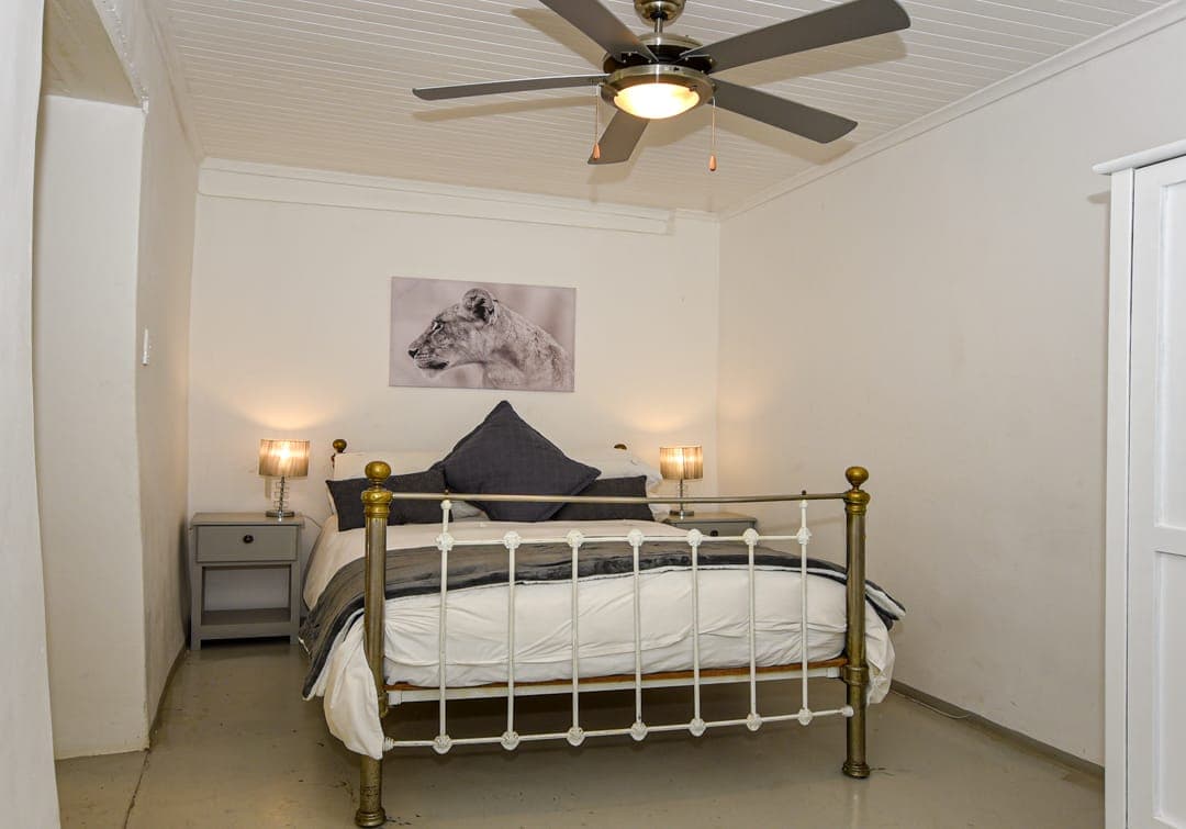 The second en-suite bedroom at White House Cottage, with a brass-and-iron bed and grey linen.