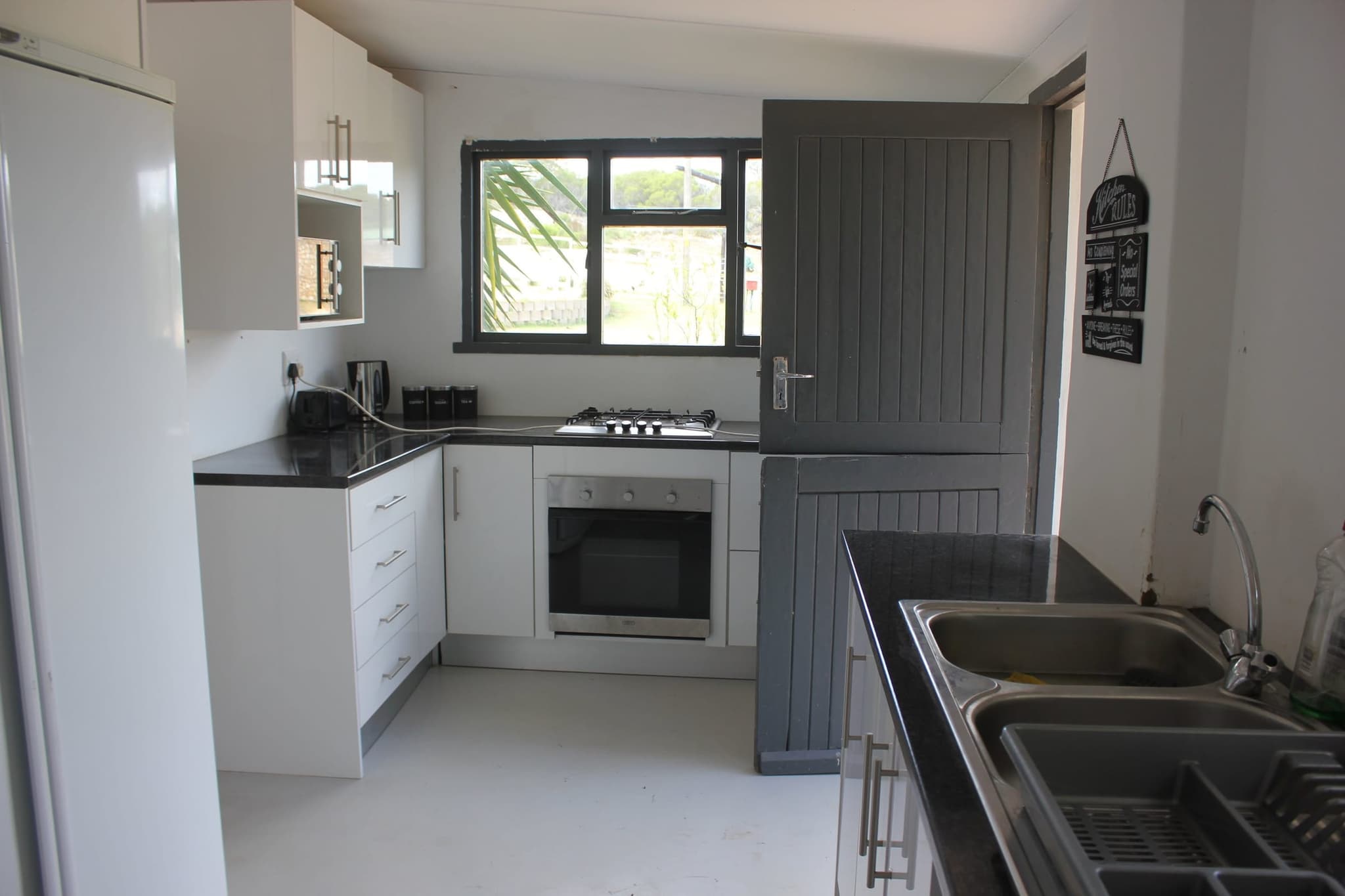 The White House Cottage kitchen with a gas hob and oven, and the stable door out to the braai area.