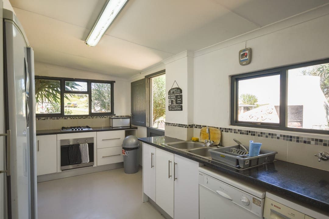 The White House kitchen: white cupboards, black counters, a gas hob and oven, and windows over the garden.