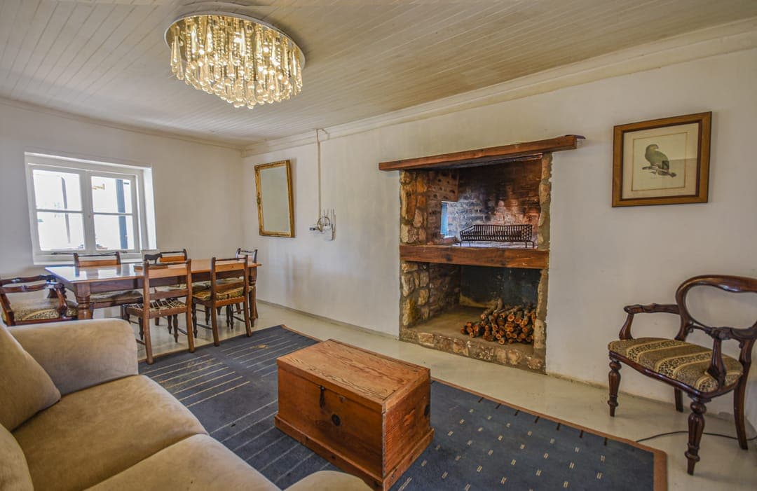 The White House lounge and dining room with a crystal chandelier, an open fireplace and a dining table by the window.