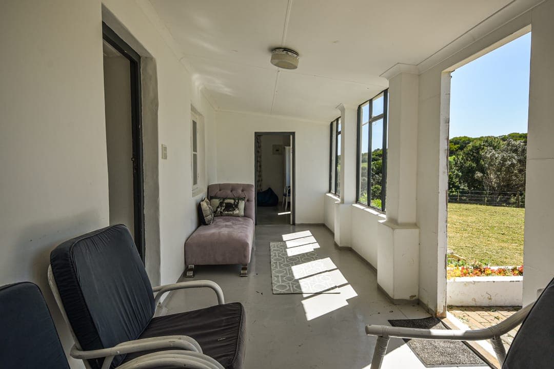 The White House Cottage sunroom with easy chairs and a daybed, the garden through the windows.