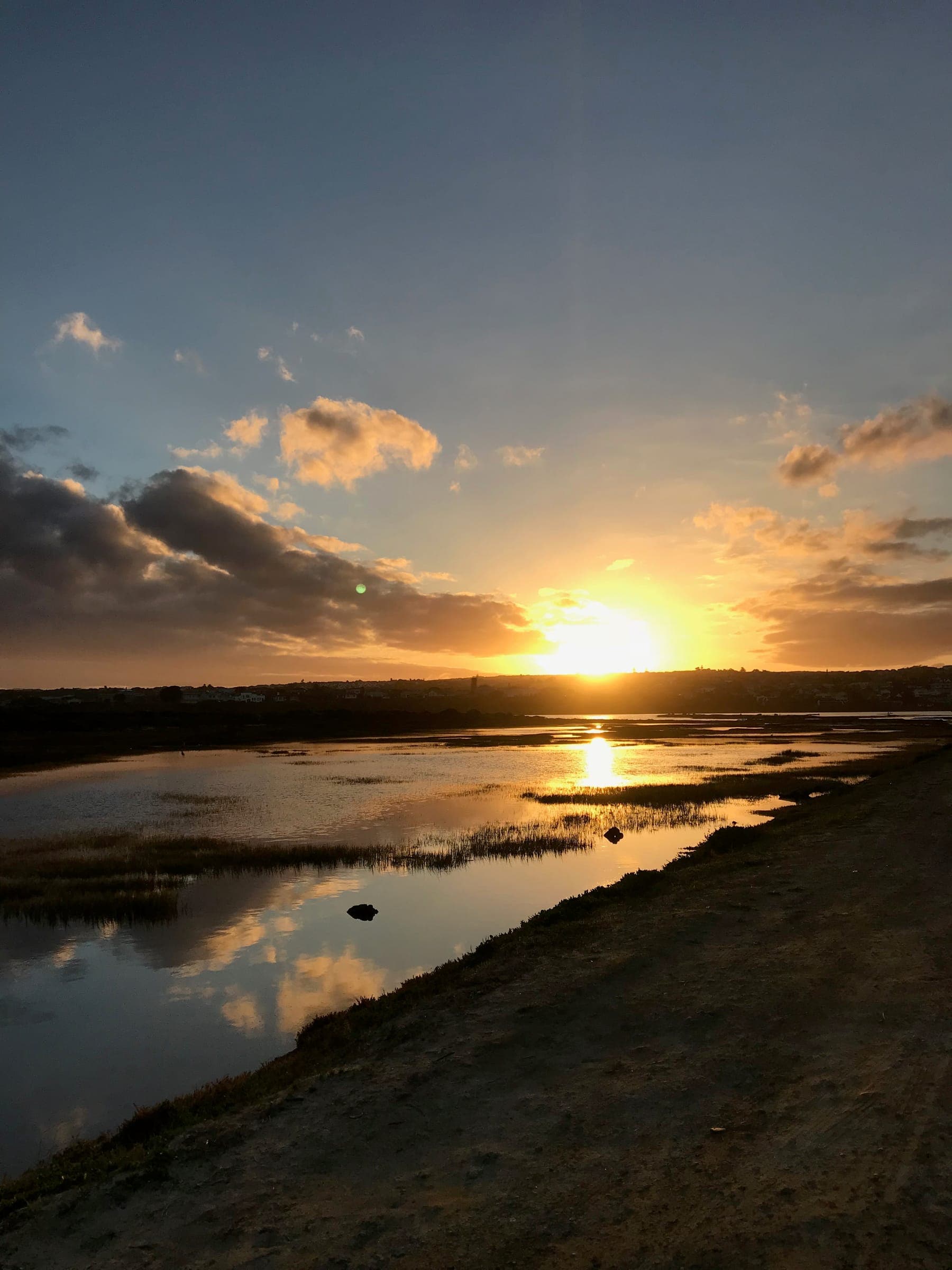 The sun going down over the Goukou estuary, the channels and reeds lit gold.