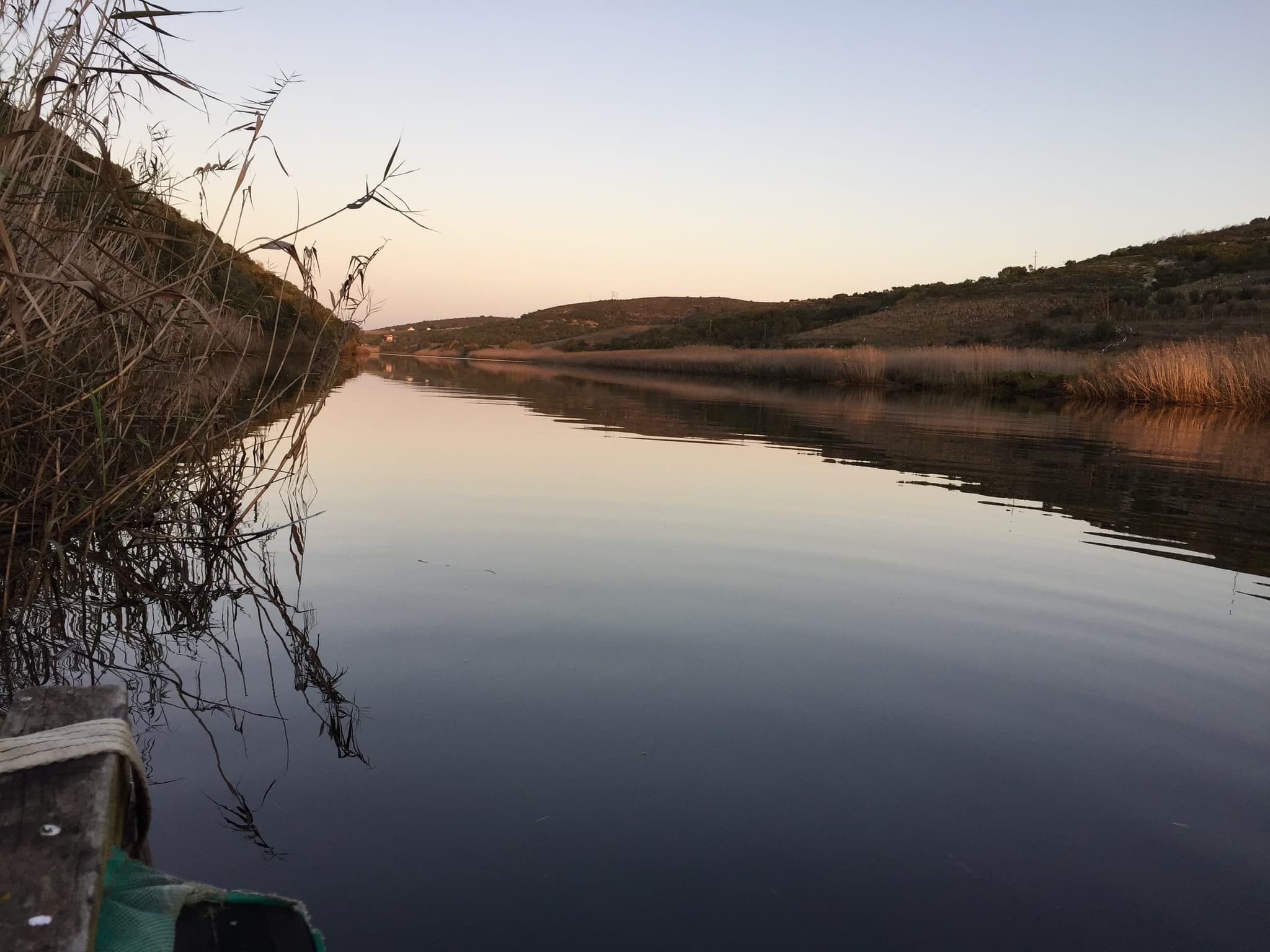 The Goukou at dusk, the still water reflecting the reeds and the pink sky.