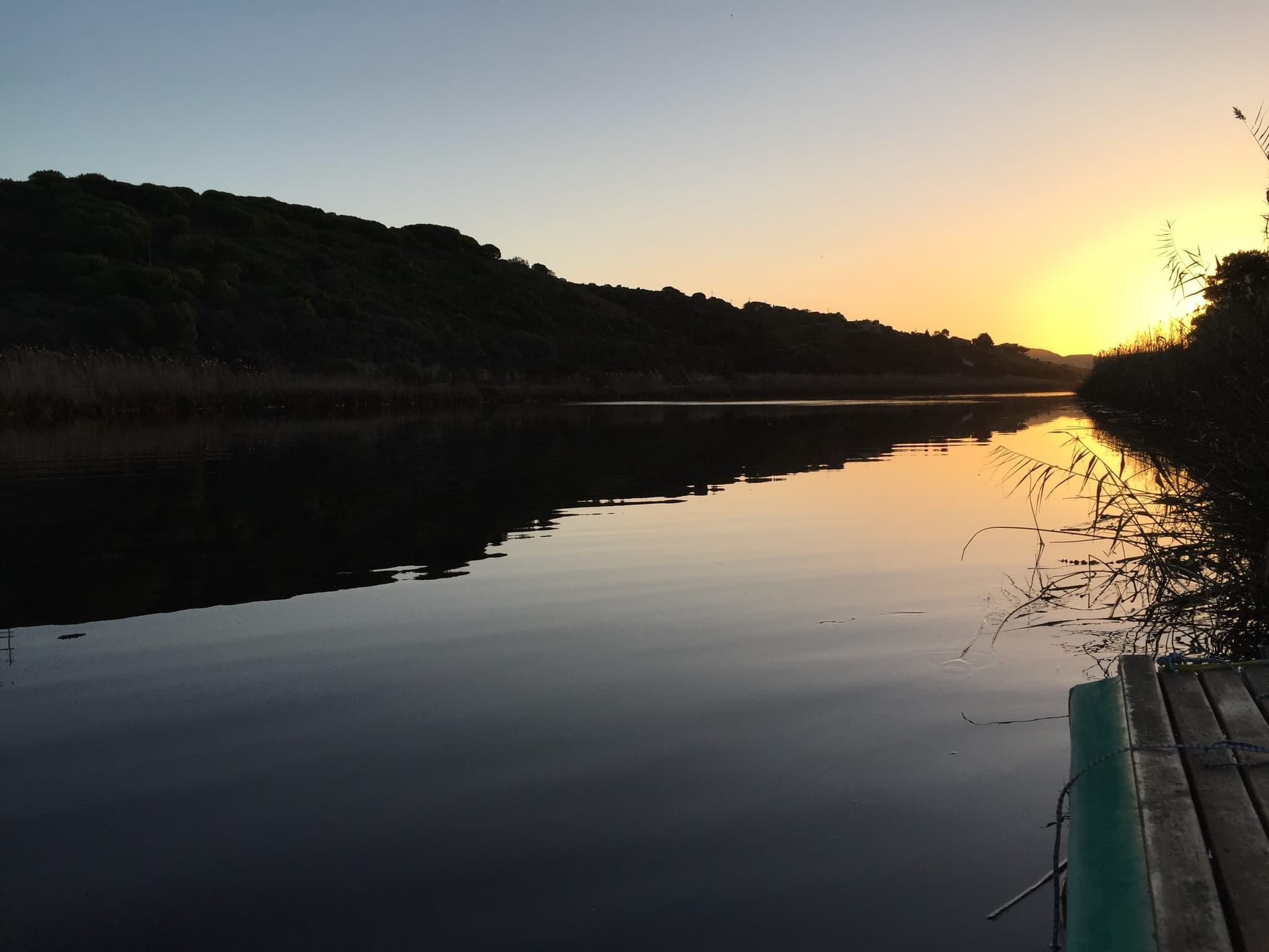 The Goukou at sunset, still as glass and mirroring the wooded hills.